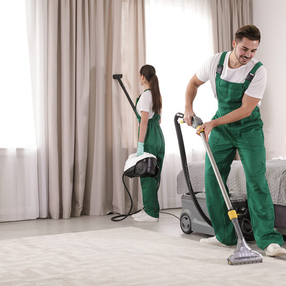 Team of janitors cleaning bedroom with professional equipment