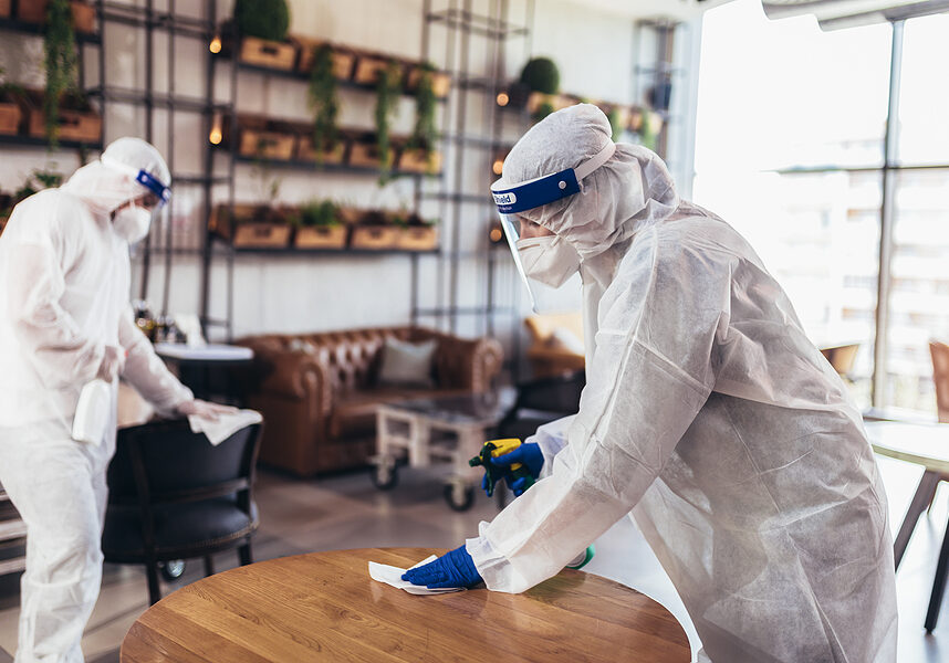 Professional workers in hazmat suits disinfecting indoor of cafe or restaurant, pandemic health risk, coronavirus
